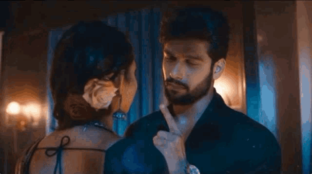 a man and a woman are standing next to each other and the man is pointing at the woman 's face .