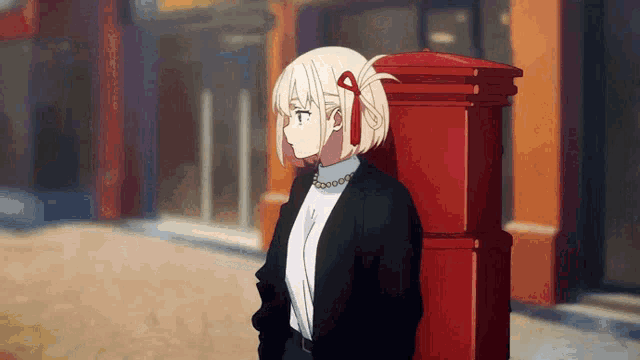 a girl leaning against a red post box in a city