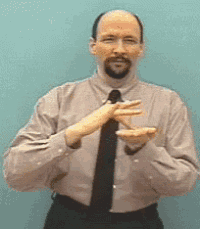 a man with a beard wearing a shirt and tie is making a hand gesture