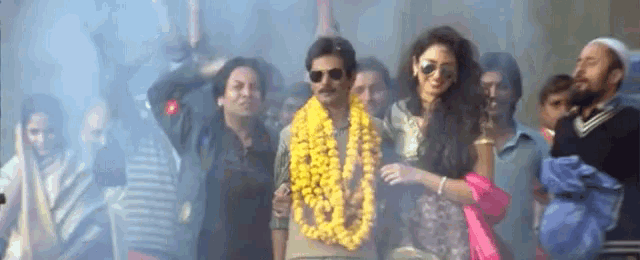 a group of people are standing in a crowd with a man wearing a garland around his neck