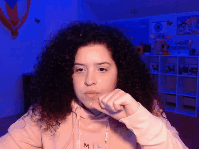 a woman with curly hair wearing a mil hoodie