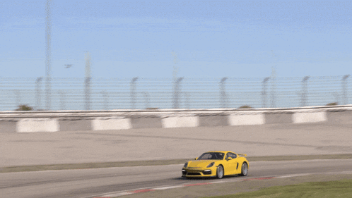 a yellow sports car is driving down a track