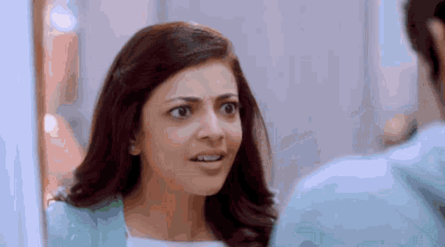 a woman is looking at herself in a mirror and making a surprised face .