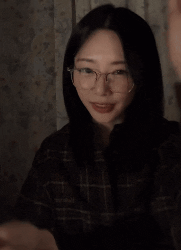 a woman wearing glasses is clapping her hands and smiling