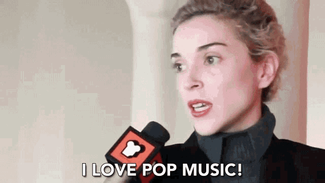 a woman is holding a microphone in her hand and saying `` i love pop music '' .