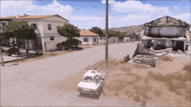 a white car is parked on the side of a road in front of a destroyed building