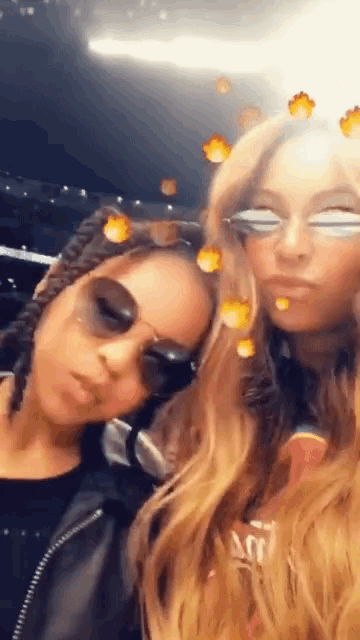 two women wearing sunglasses pose for a photo together