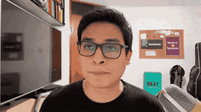 a man wearing glasses and a black shirt stands in front of a microphone and a sign that says beat