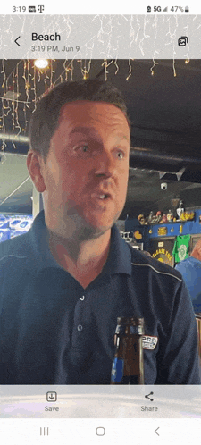 a man wearing a blue shirt with the word beach on the front