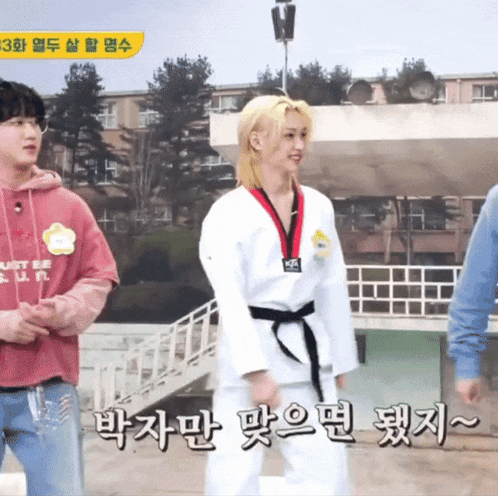 a girl in a taekwondo uniform is standing next to a man in a pink shirt