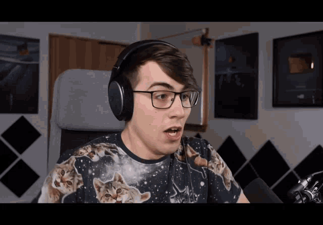 a man wearing glasses and headphones has a cat shirt on