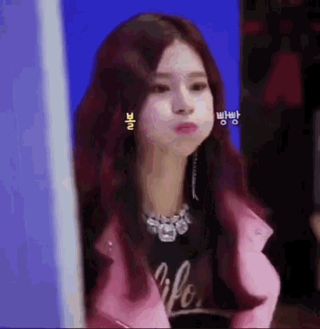 a woman with long red hair is wearing a pink jacket and earrings .