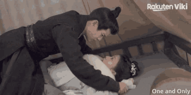 a man and a woman are laying on a bed with rakuten viki written in the corner