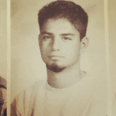 a black and white photo of a young man with a beard and a white shirt