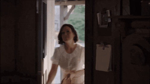 a woman in a white shirt is standing in a doorway