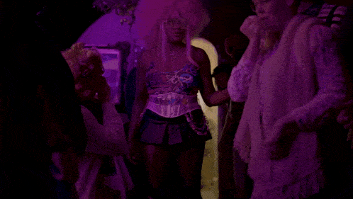 a woman in a pink wig is standing in a crowd