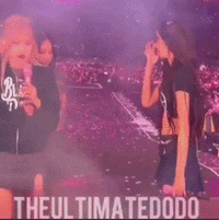 three girls wearing black pink shirts are standing on a stage .