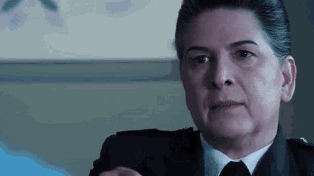 a woman in a suit and tie is sitting in a room .