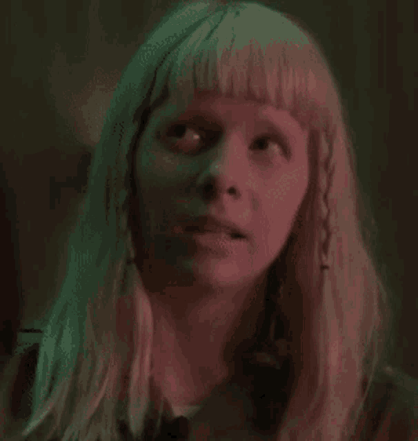 a close up of a woman 's face in a dark room with pink lights .