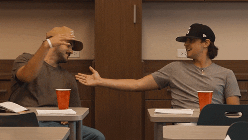a man wearing a hat with the letter j on it talks to another man