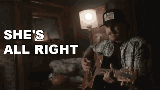 a man is playing a guitar in a dark room and the words she 's all right are above him .