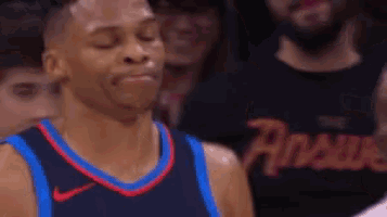 a basketball player with his eyes closed is standing in front of a crowd of people .