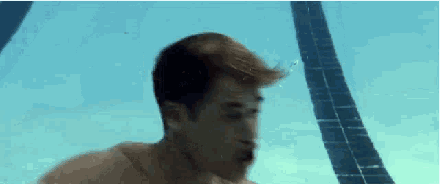 a shirtless man is swimming underwater in a pool .