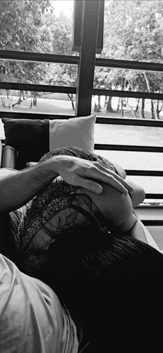 a black and white photo of a woman laying on a man 's lap
