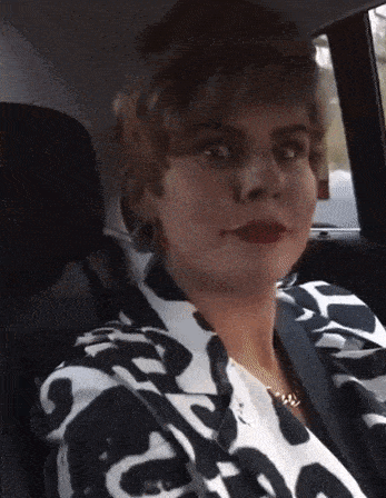 a woman wearing a black and white shirt is sitting in a car