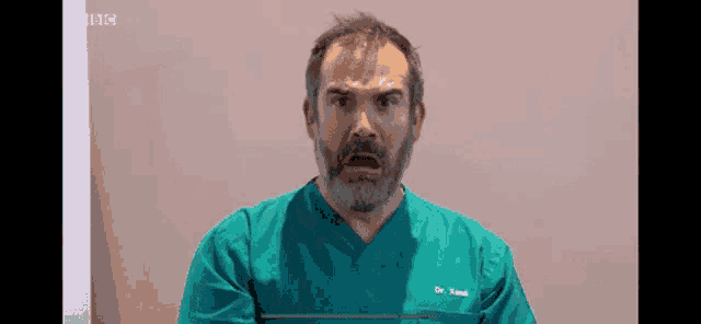 a man with a beard is wearing a green scrub top that says dr. samuel on it