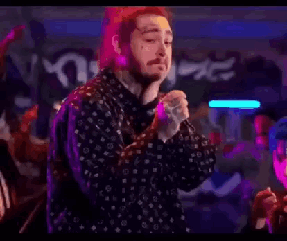 a man with a beard is singing into a microphone in front of a crowd at a concert .