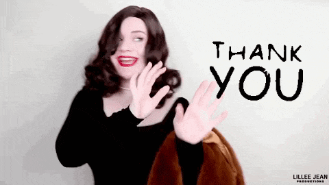 a woman in a wig is waving her hand in front of a sign that says `` thank you '' .