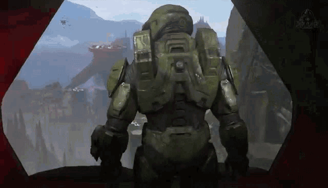 a man in a green armor is standing in front of a window looking out .