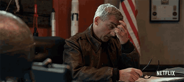 a man sitting at a desk with a netflix logo on the bottom right