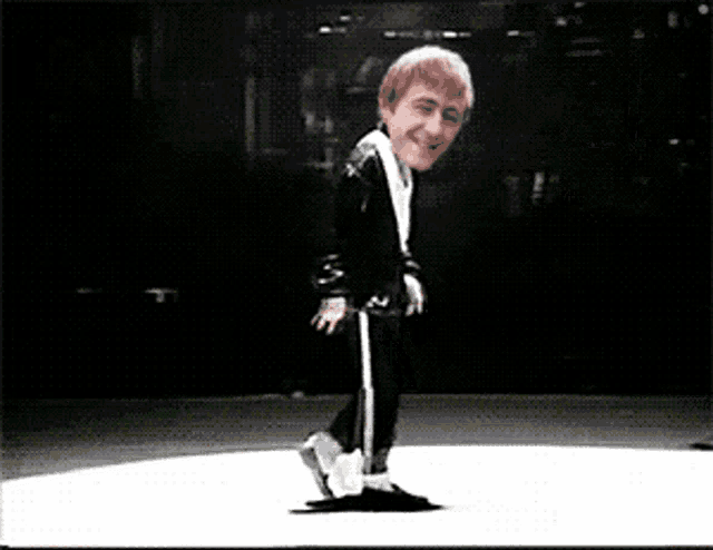 a man in a black suit is dancing on a stage