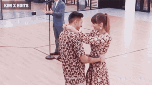 a man and a woman are dancing on a dance floor while a man stands behind them .