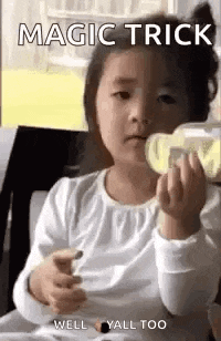 a little girl is drinking milk from a bottle and eating a cookie .