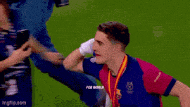 a soccer player is wearing a medal around his neck while standing on a soccer field .