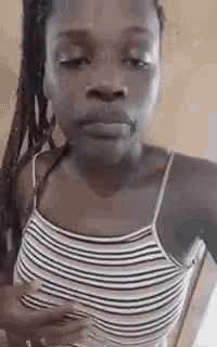 a woman in a striped tank top is making a face .