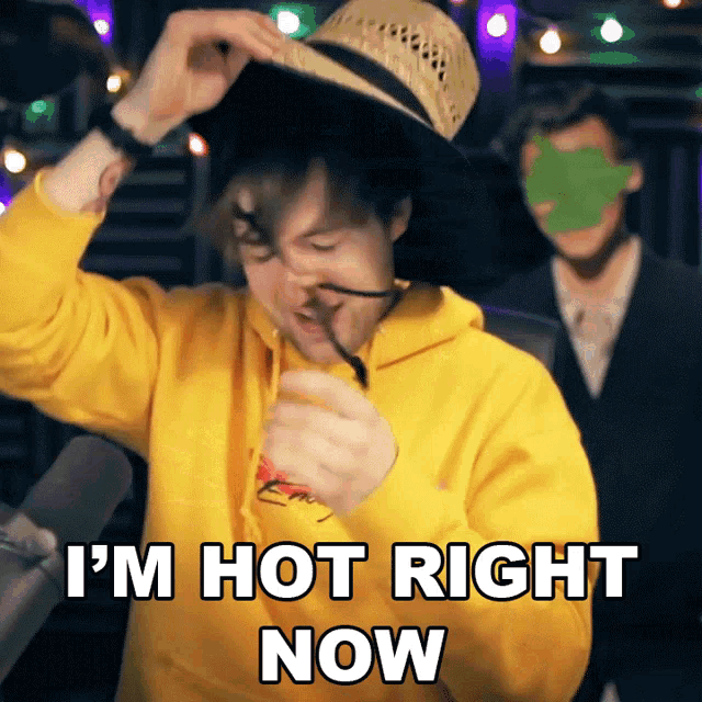 a man wearing a straw hat and a yellow hoodie says i 'm hot right now