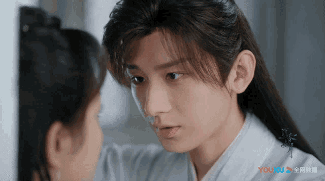 a close up of a person 's face with a youku logo in the background