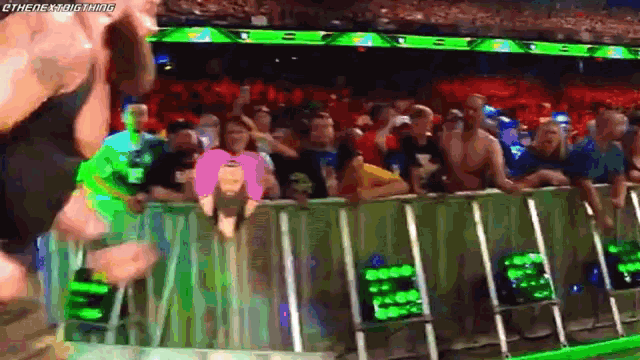 a crowd of people watching a wrestling match in a stadium with a sign that says ' wwe ' on it .