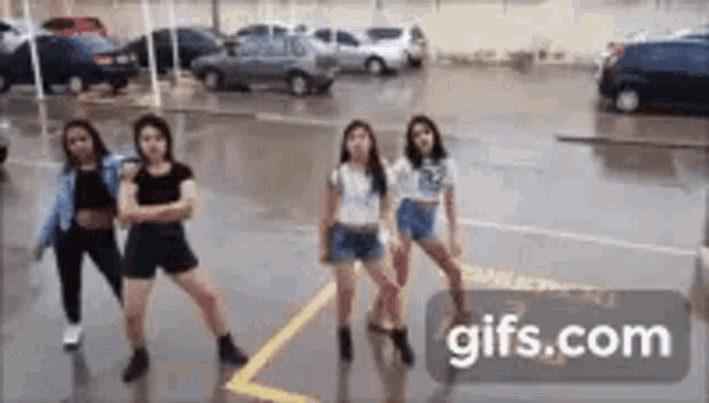 a group of young girls are dancing in a parking lot in the rain .