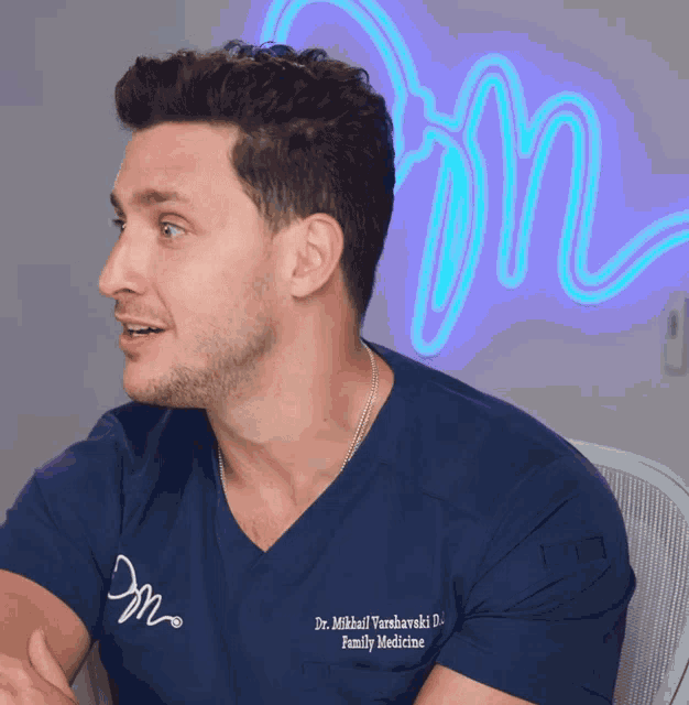 a man wearing a blue shirt that says dr. mikhail vanshawski family medicine