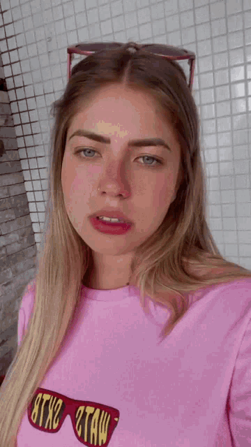 a woman wearing sunglasses and a pink shirt that says 8tx2 2taw