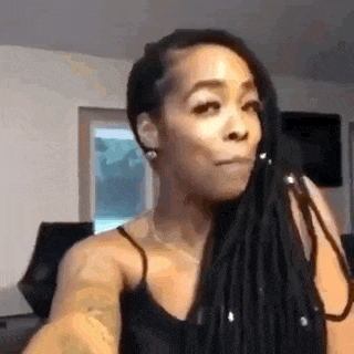 a woman with dreadlocks is taking a selfie with her phone .
