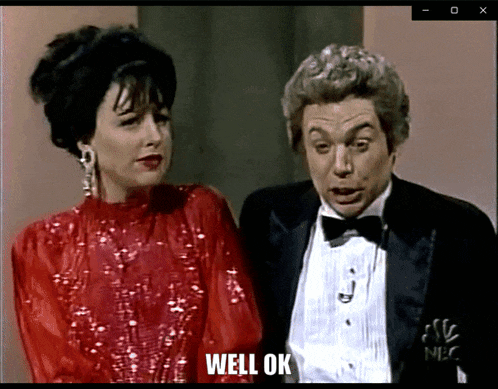 a man in a tuxedo and a woman in a red dress are standing next to each other and the man says well ok