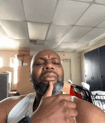 a man with a beard is making a funny face in a room with a fire exit sign in the background