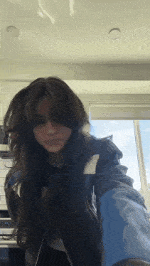 a girl with long hair is taking a selfie in a kitchen .