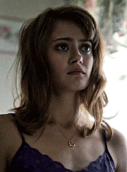 a woman wearing a purple tank top and a necklace with a heart pendant